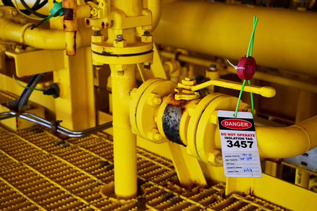 Lockout tagout danger tag and lock on a yellow industrial valve