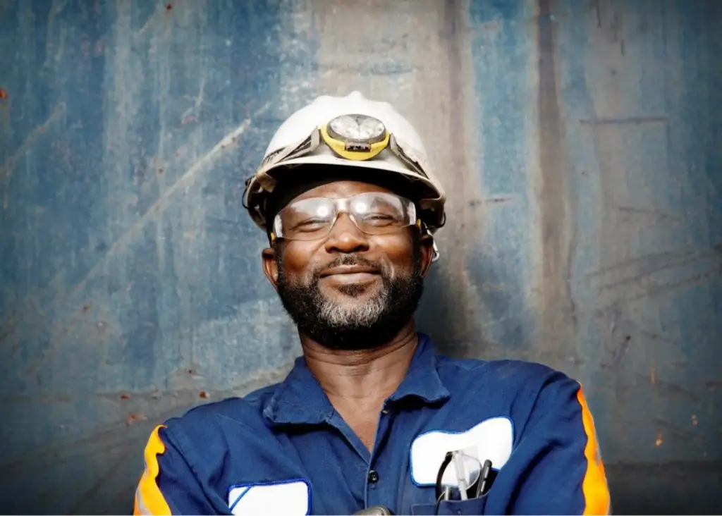 Industrial worker in hard hat with headlamp and safety glasses smiling confidently
