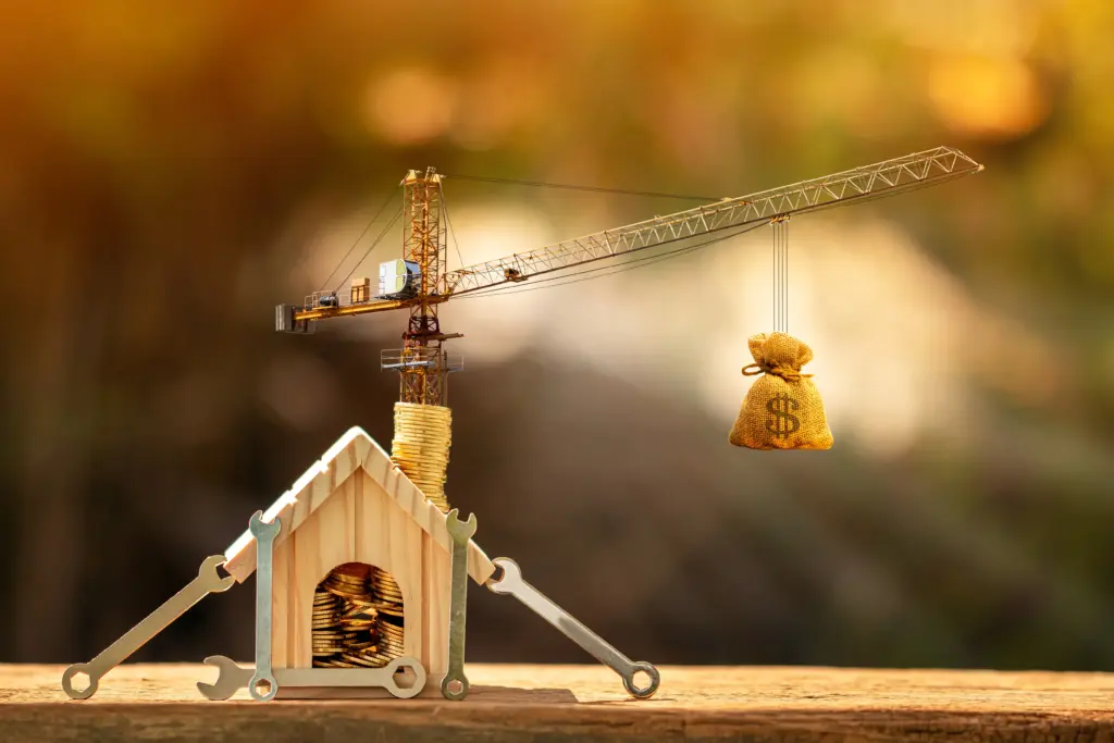 Crane building house with coins and money bag