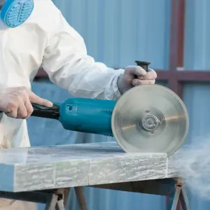 Worker cutting stone slab with circular saw